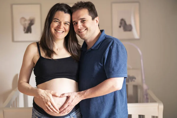 Пара беременных в детской комнате — стоковое фото