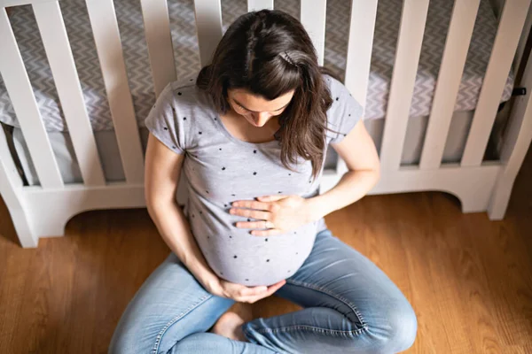 Uma bela mãe grávida no quarto do bebê — Fotografia de Stock