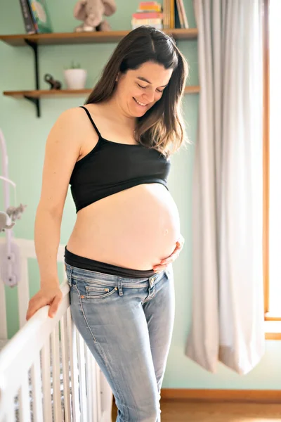 Uma bela mãe grávida no quarto do bebê — Fotografia de Stock