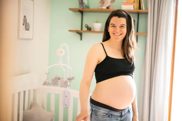 Una hermosa madre embarazada en la habitación del bebé —  Fotos de Stock