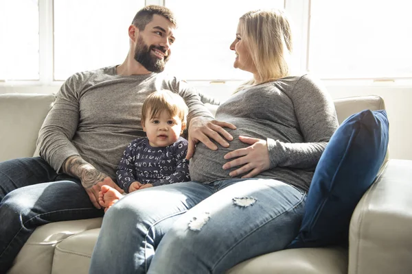 Vakker, gravid mor og far med sine barn i stua – stockfoto