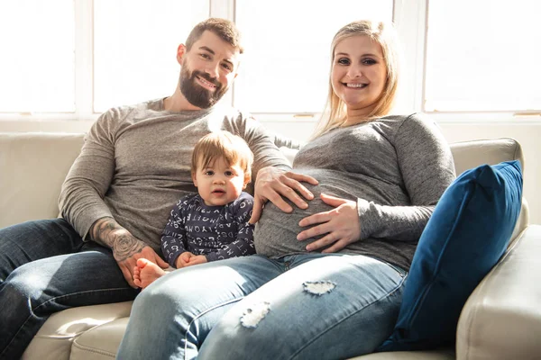 Vakker, gravid mor og far med sine barn i stua – stockfoto