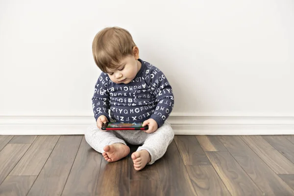 Een kleine jongen peuter zitten en kijken speelt in de tablet mobiele telefoon — Stockfoto