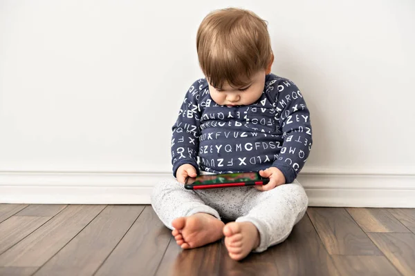 Um menino criança sentada e assistindo toca no celular tablet — Fotografia de Stock