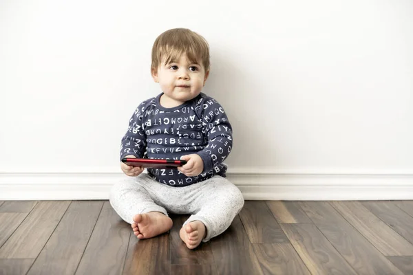 Um menino criança sentada e assistindo toca no celular tablet — Fotografia de Stock