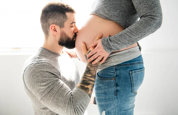 Uma bela mulher grávida e seu marido bonito olhar de perto t a barriga — Fotografia de Stock