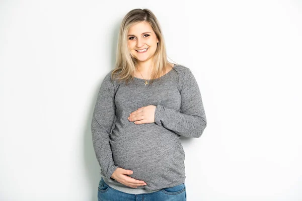 Donna incinta accarezzando la pancia su sfondo bianco — Foto Stock