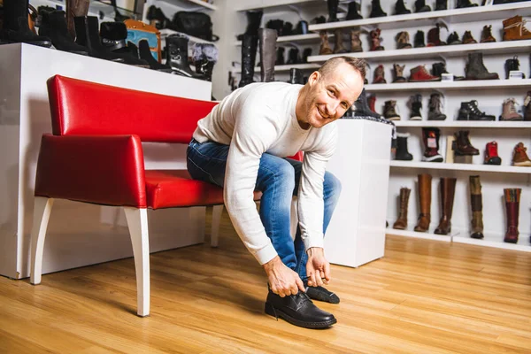 Een man zoekt nieuwe schoenen in de schoenenwinkel. — Stockfoto