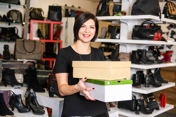 A sale, shopping and people concept happy young woman or shop assistant with shoe boxes at store — Stock Photo, Image