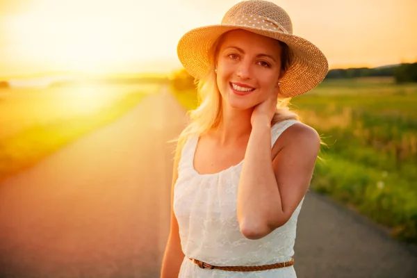 Frau auf einem Heufeld bei Sonnenuntergang mit Hut — Stockfoto