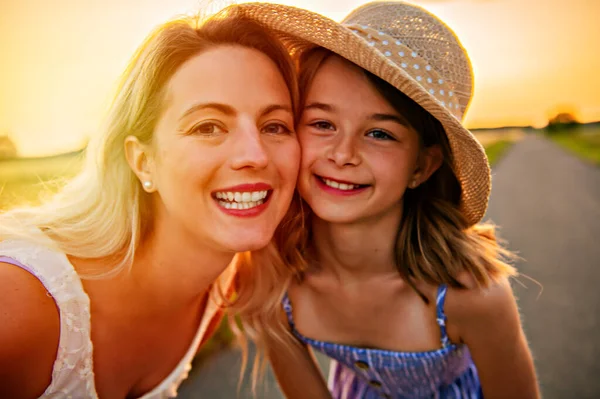 Glückliche Familie bei Sonnenuntergang. Mutter und Tochter haben Spaß und spielen in der Natur — Stockfoto