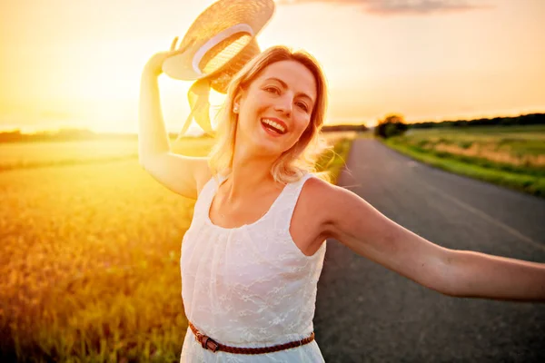 Frau auf einem Heufeld bei Sonnenuntergang mit Hut — Stockfoto