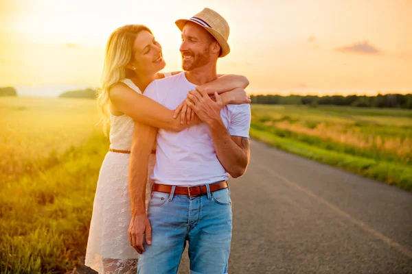 Happy couple at sunset. Man and woman having fun playing in nature — Stock Photo, Image