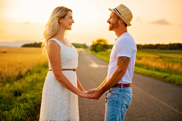 Pareja feliz al atardecer. Hombre y mujer divirtiéndose jugando en la naturaleza —  Fotos de Stock