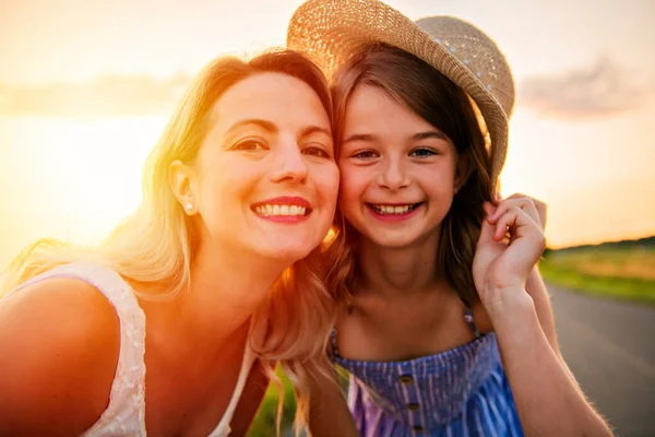 Glückliche Familie bei Sonnenuntergang. Mutter und Tochter haben Spaß und spielen in der Natur — Stockfoto