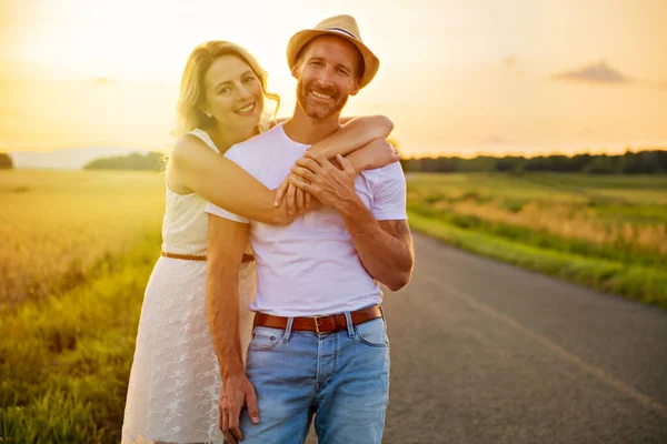 Coppia felice al tramonto. Uomo e donna si divertono a giocare in natura — Foto Stock