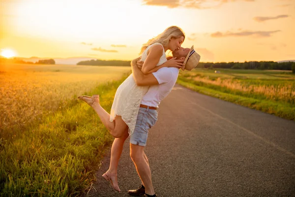 Pareja feliz al atardecer. Hombre y mujer divirtiéndose jugando en la naturaleza —  Fotos de Stock