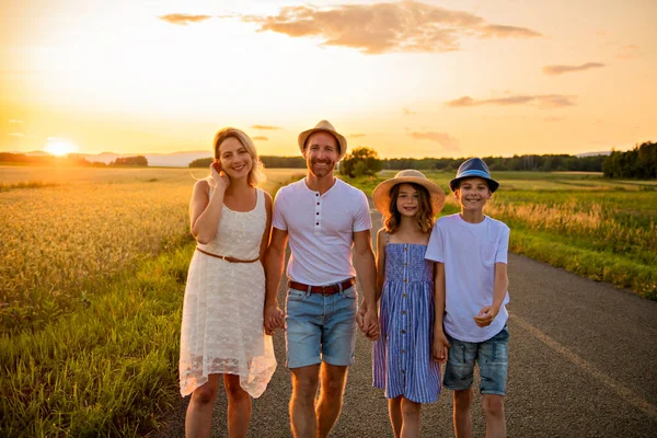 Família feliz ao pôr do sol. Eles se divertindo e brincando na natureza ao pôr do sol — Fotografia de Stock