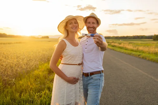 Um casal ao pôr-do-sol com teste de bebé positivo — Fotografia de Stock