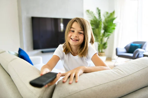 リモコンを持ってテレビ番組を見ている女の子 — ストック写真