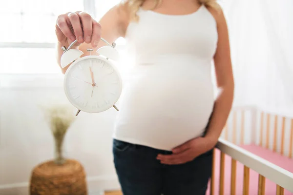 Een zwangere vrouw met klok thuis — Stockfoto