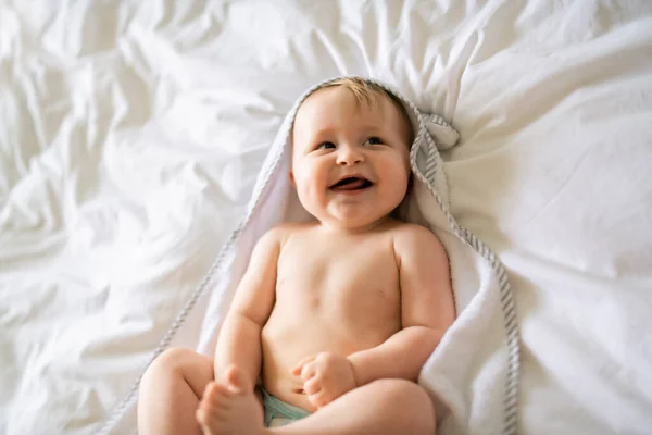 Um bebê bonito em roupa de cama branca em casa — Fotografia de Stock