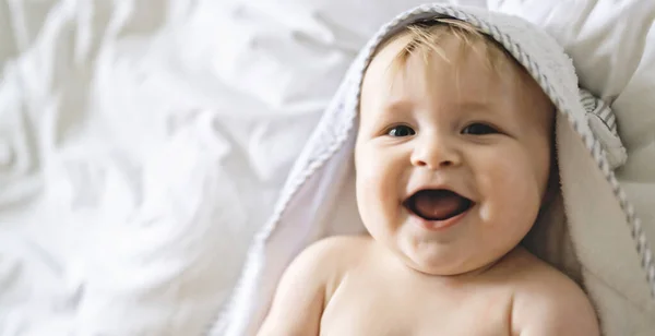 Un lindo bebé en ropa de cama blanca en casa — Foto de Stock