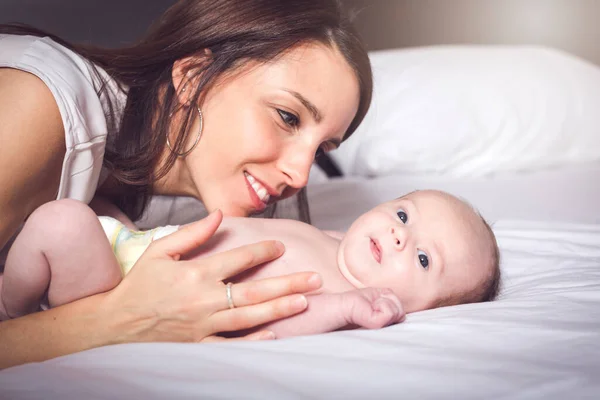 En lycklig mamma med barnet i sängen — Stockfoto