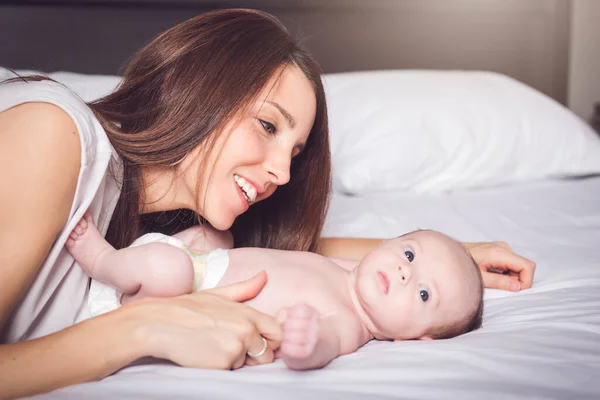 Una madre feliz con el bebé en la cama — Foto de Stock