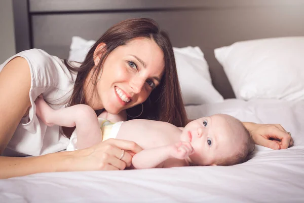 Een gelukkige moeder met baby op bed — Stockfoto