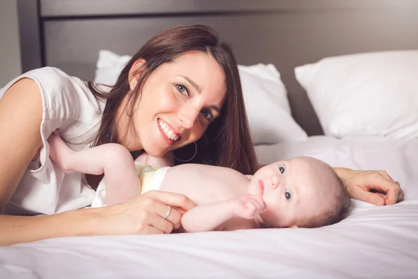 Une mère heureuse avec bébé au lit — Photo