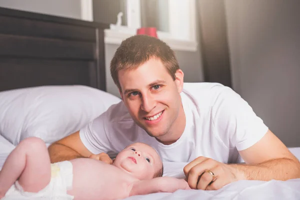 Genç baba ve yeni doğmuş bebek evde yatıyorlar. — Stok fotoğraf