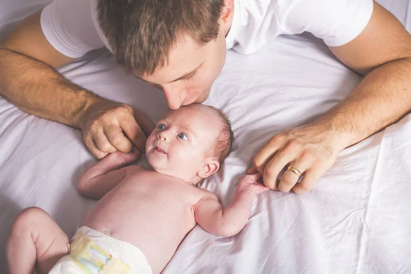 Jovem pai e bebê recém-nascido menina na cama em casa — Fotografia de Stock