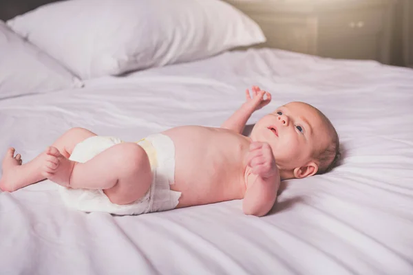 Bebê tranquilo deitado em uma cama no quarto dos pais — Fotografia de Stock