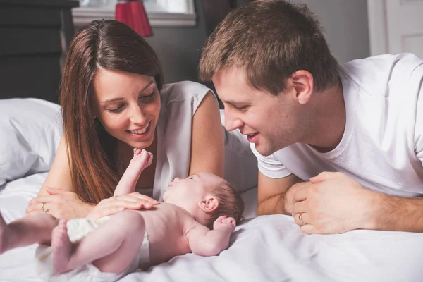 Mother father and baby child on a white bed. — Stock Photo, Image