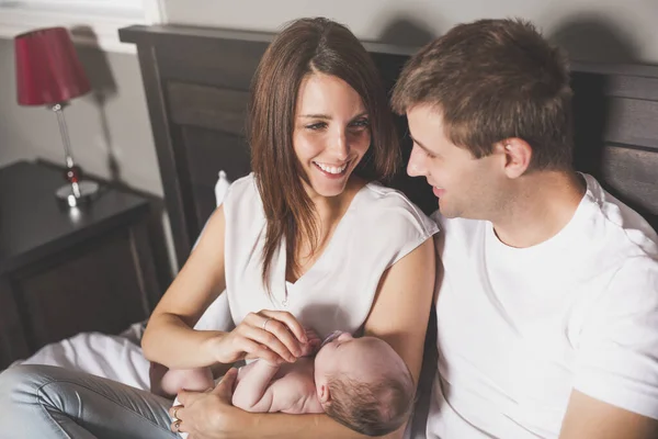 Mother father and baby child on a white bed. — Stock Photo, Image