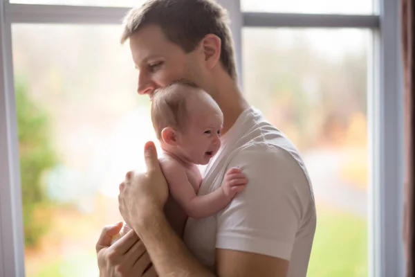 Pai da família feliz com bebê recém-nascido na frente da janela — Fotografia de Stock