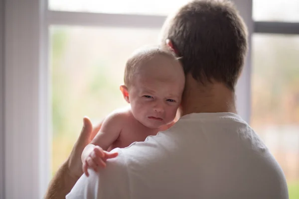 Happy family father with newborn baby in front of window — Stock Photo, Image