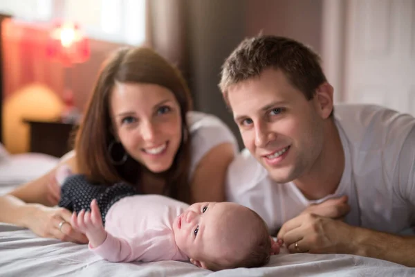 Mother father and baby child on a white bed. — Stock Photo, Image