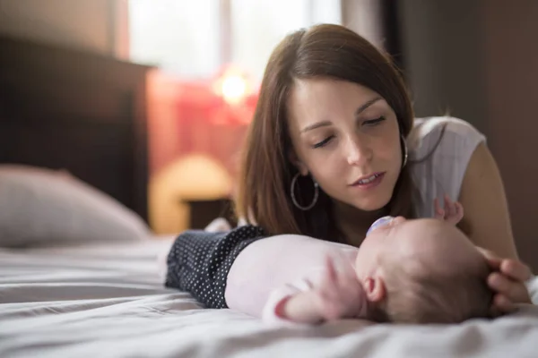 Una madre feliz con el bebé en la cama — Foto de Stock