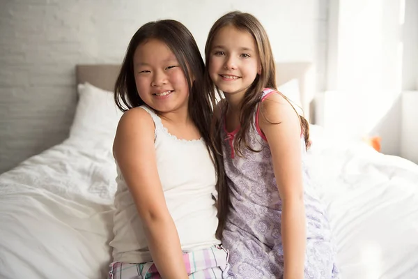 Δυο κοριτσάκια ξαπλωμένα στο κρεβάτι με πιτζάμες. — Φωτογραφία Αρχείου