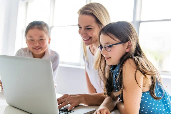 Ребенок с технологическим планшетом и ноутбуком в классе учитель на заднем плане — стоковое фото