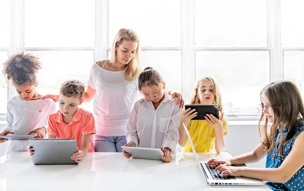 Dziecko z tabletem technologicznym i laptopem w klasie nauczyciel na tle — Zdjęcie stockowe
