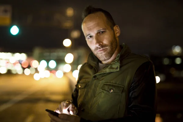 Fešák používající chytrý telefon mobilní ve městě v noci — Stock fotografie