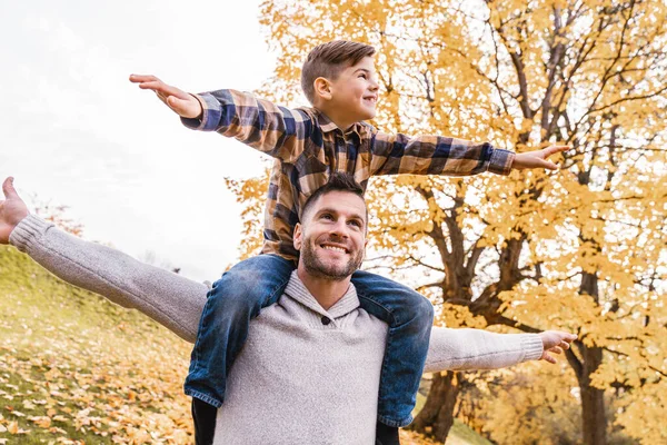 Lycklig familj far och barn pojke på axeln i höst löv falla i parken — Stockfoto