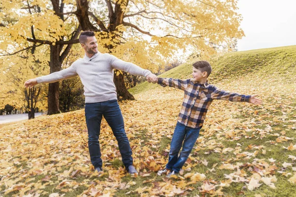 Lycklig familj far och barn pojke i höst löv faller i parken håller hand tillsammans — Stockfoto