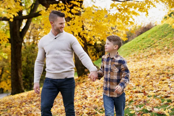 Heureux père de famille et enfant garçon dans la feuille d'automne tombent dans le parc tenant la main ensemble — Photo