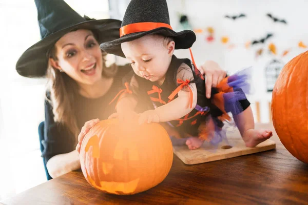 Familie moeder en baby dochter op de keukentafel klaar voor de Halloween met pompoen — Stockfoto