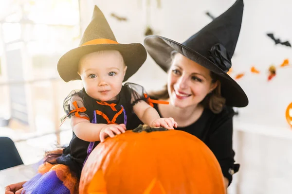 Familie moeder en baby dochter op de keukentafel klaar voor de Halloween met pompoen — Stockfoto