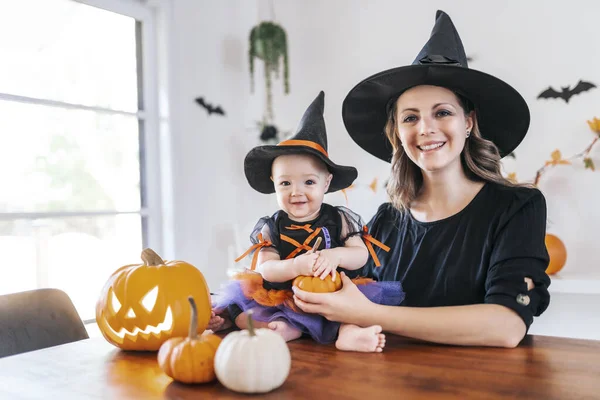 Familie moeder en baby dochter op de keukentafel klaar voor de Halloween met pompoen — Stockfoto